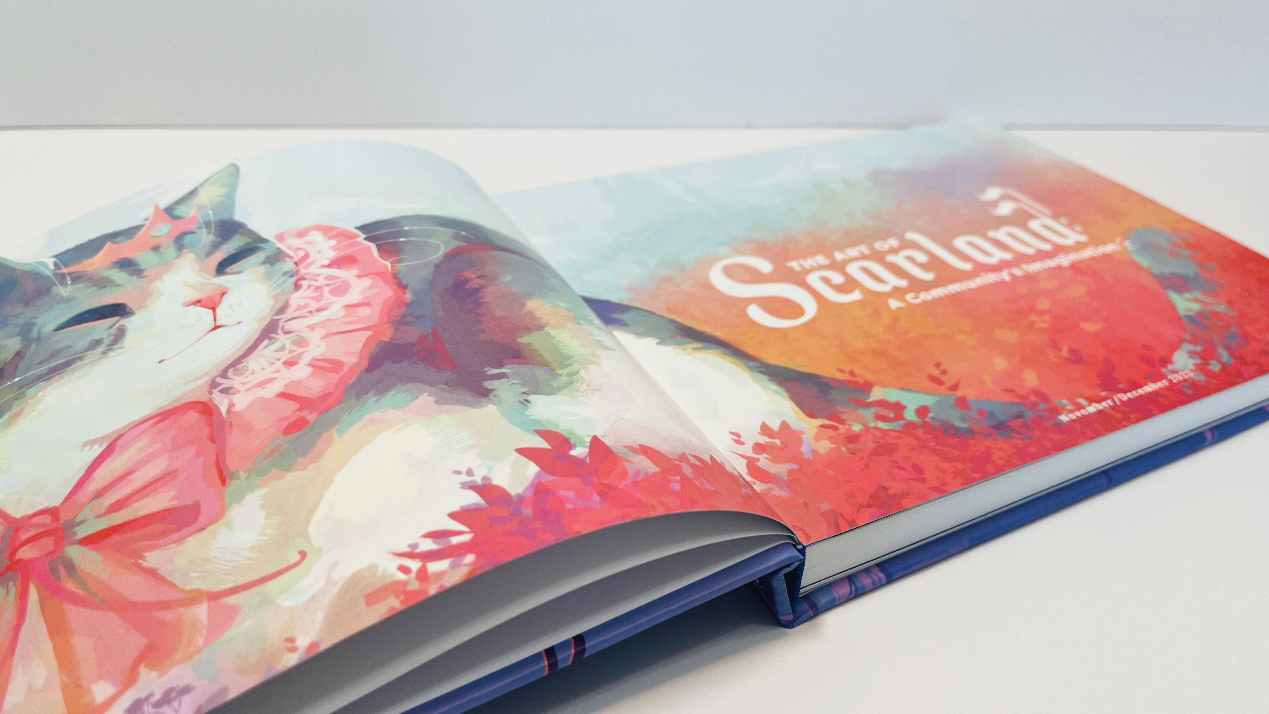 The Scarland Artbook laid flat on a white surface with a white background. It is open to two of the first pages. The pages showcase a beautiful Queen Jellie illustration by Julia Cocoabats, and the title text reads, 